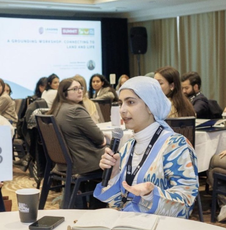 Sana speaking into a microphone at a workshop